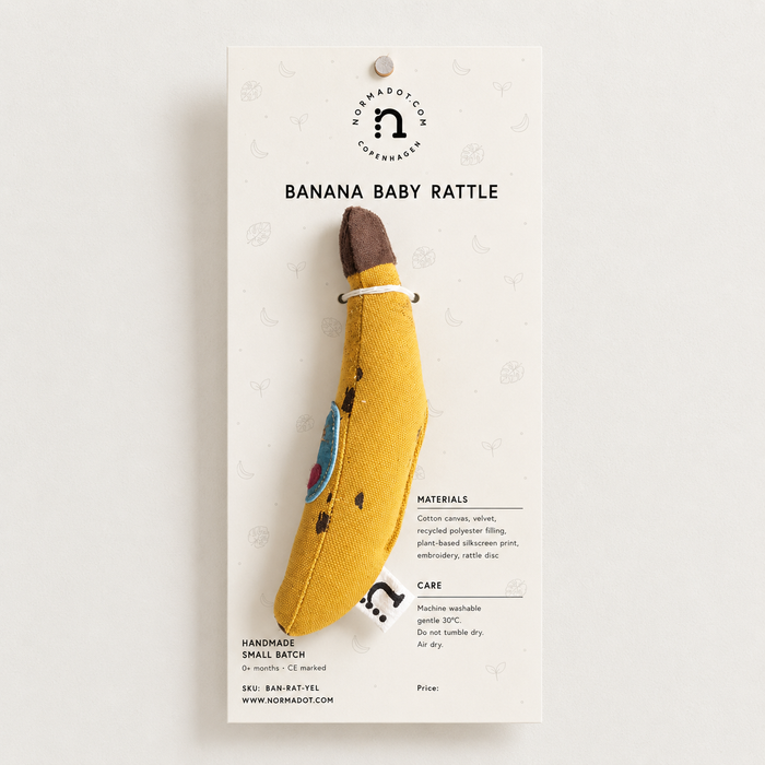 Banana baby rattle on a white background with branding and product details.