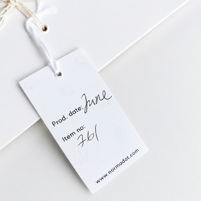 Product tag with 'June' production date and 'normadot.com' on a white background