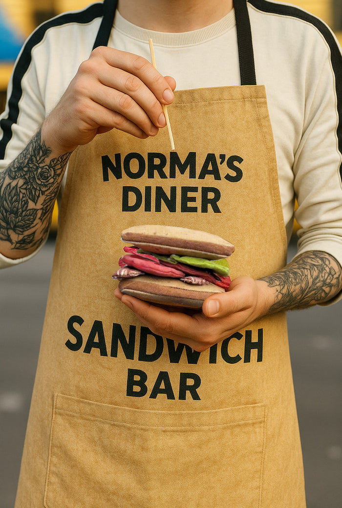 Person wearing a Norma’s Diner sandwich bar apron while holding a handmade fabric BLT sandwich play food toy.