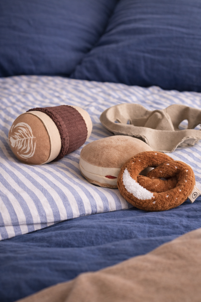 Three plush toys fabric pretzel, berliner and cappuccino cup on a blue and white striped fabric background