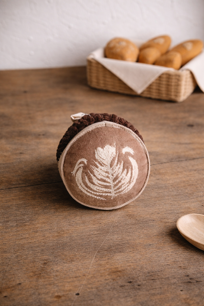 Pretend  play Fabric Cup of coffee with latte art on a wooden table with bread in the background
