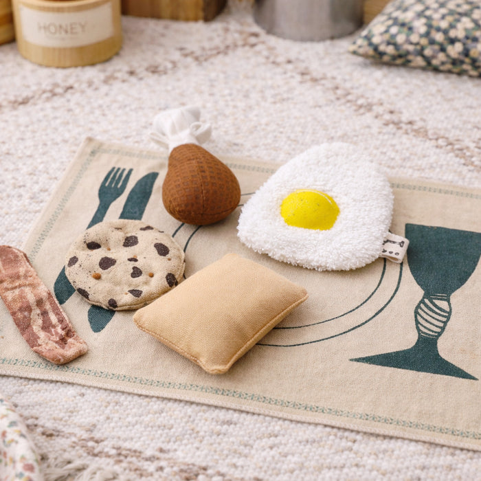 Handmade fabric breakfast play food with egg, bacon, cookie, pear and pillow on a printed play mat