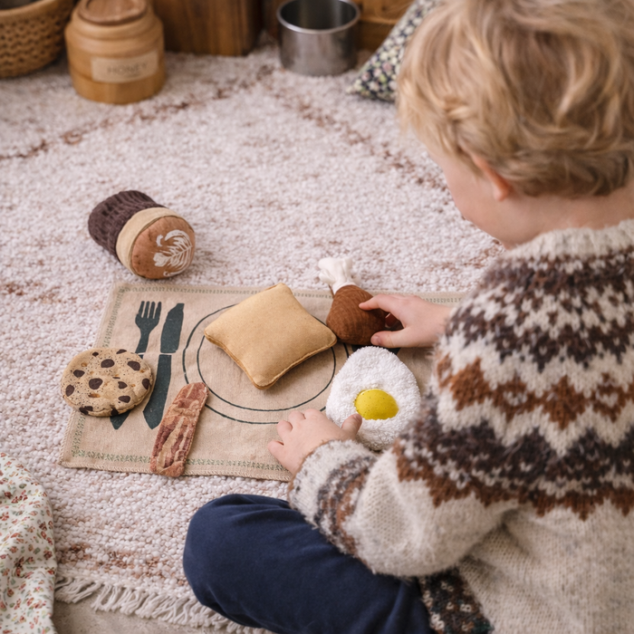 Child playing with toy food on a mat on a soft surface