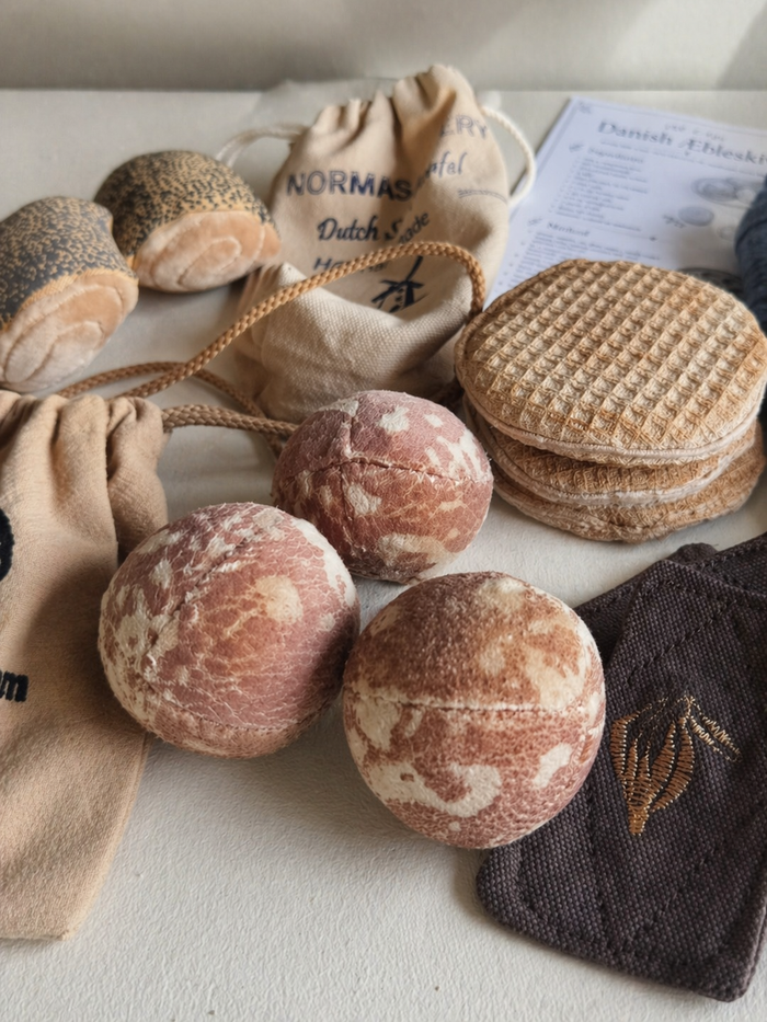 Handmade bakery play food with fabric æbleskiver, stroopwafels, bread rolls and cotton storage bags.