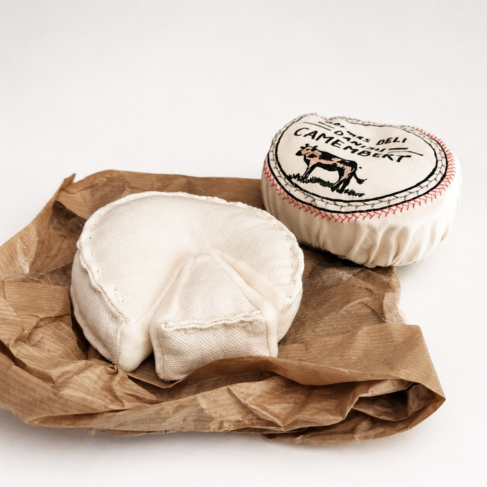 Handmade textile camembert cheese toy with removable printed cover and soft cheese wedge, displayed on brown paper as pretend play food.