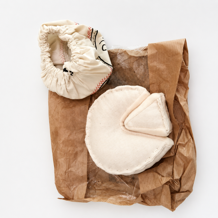 Handmade fabric camembert cheese toy with removable printed cover, soft cheese round and small cheese wedge displayed on brown paper.