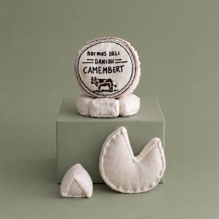 Handmade textile camembert cheese play food with removable printed cover, soft round cheese and small cheese wedge on brown paper for pretend play kitchens