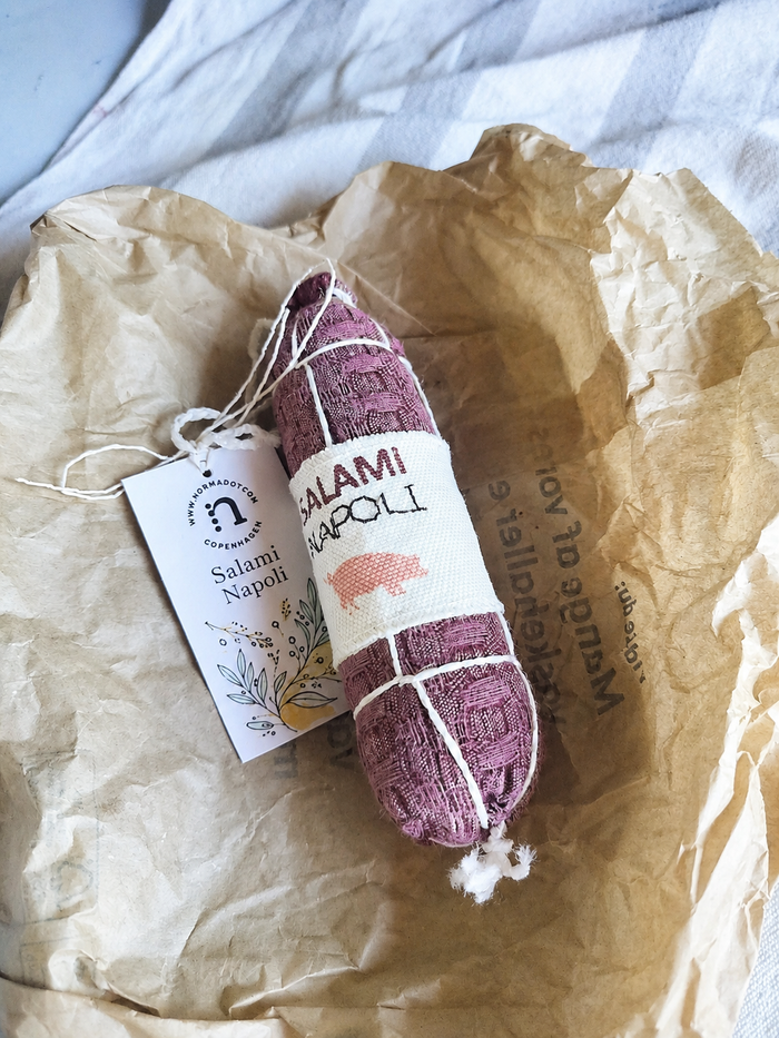 Håndlavet Salami Napoli i stof med tag, vist på krøllet papir som realistisk legemad til børnekøkken.