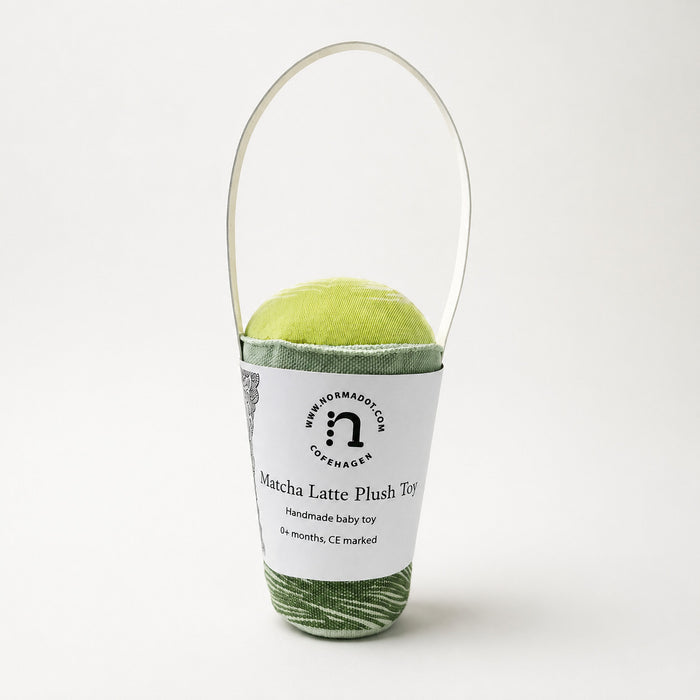 Matcha Latte Plush Toy baby rattle by normadot shown in studio on a light background with white paper packaging handle