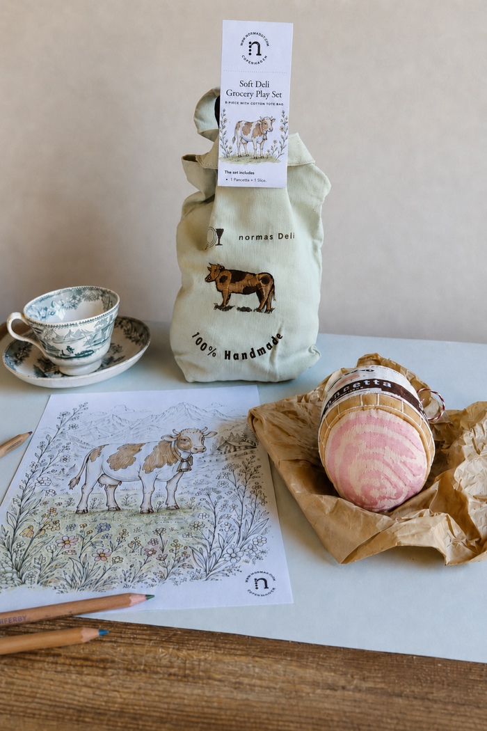 Handmade soft deli grocery play set with embroidered cotton tote bag, fabric pancetta, cow colouring sheet, coloured pencils and vintage teacup on a light table
