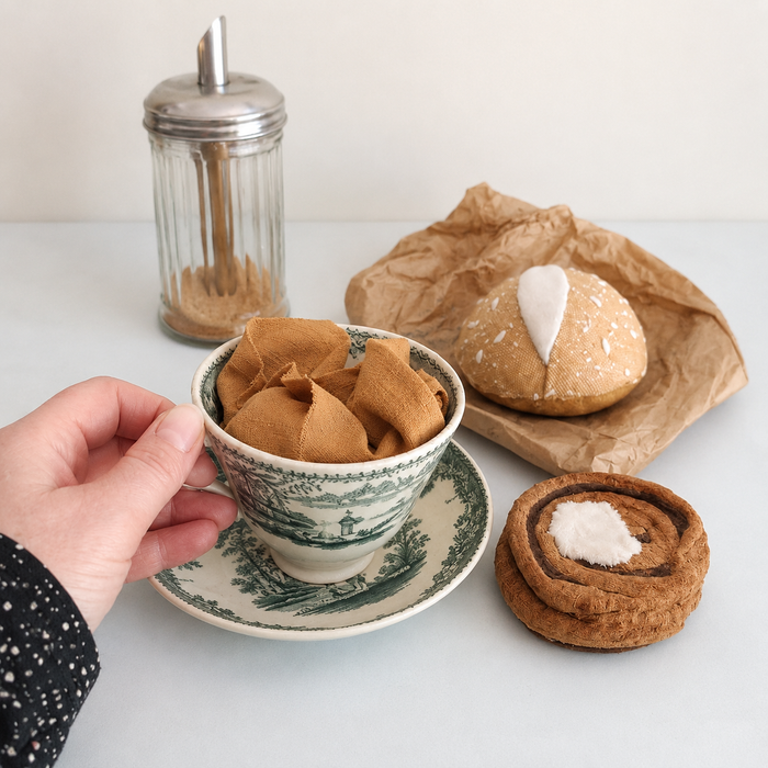 Handmade Danish kanelsnegl fabric play food styled with a vintage tea cup, cinnamon shaker and handmade bread roll