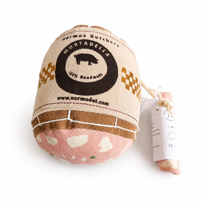 Small fabric package resembling a pretend play mortadella with a visible brand label on a white background