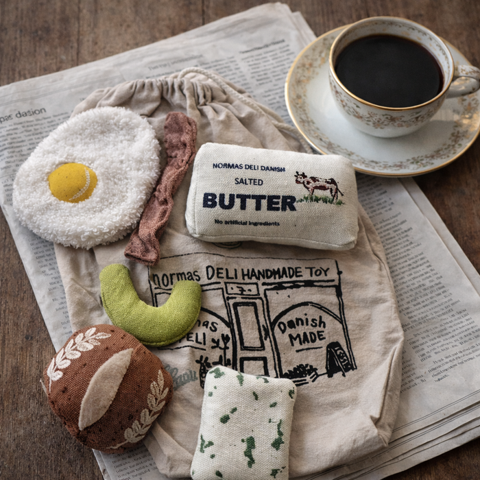 Handmade breakfast play food set with soft fabric fried egg, bacon, butter, cucumber, bread roll and cotton deli bag styled with a cup of coffee