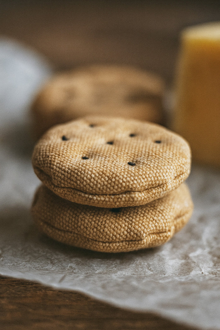 Stack of round fabric play food sesame crackers on a textured surface