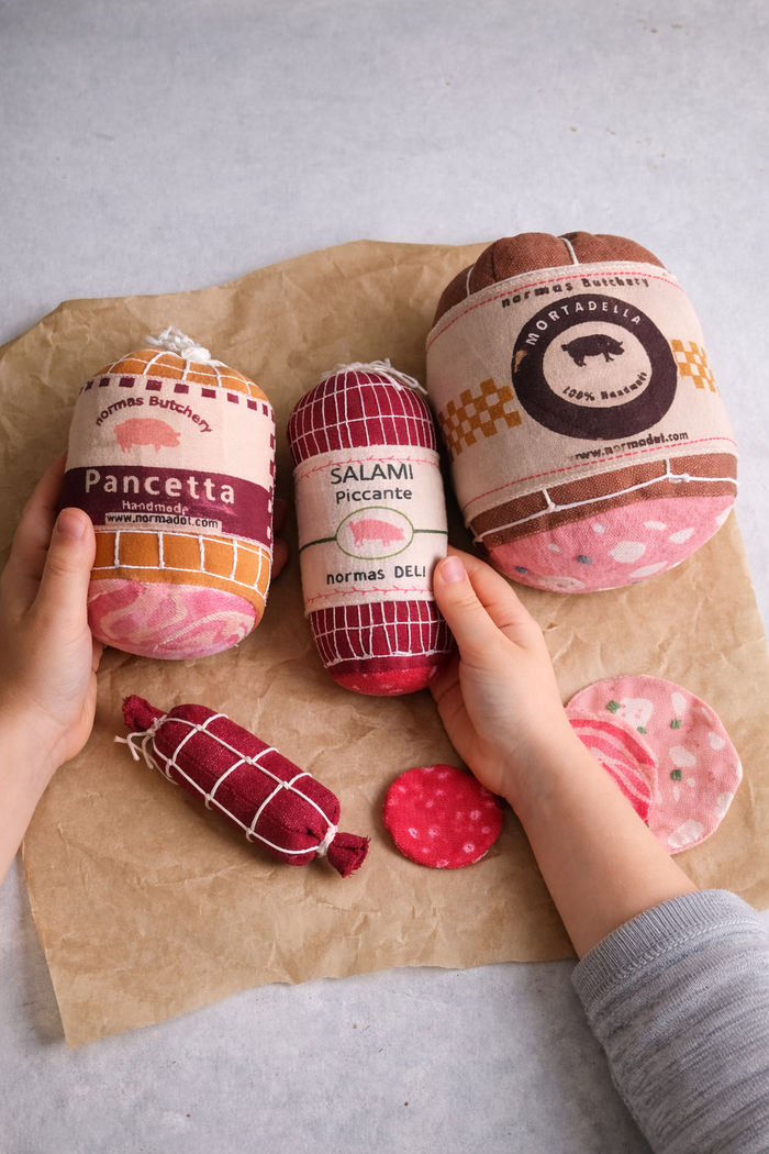 Assorted cured play food meats on brown paper with visible branding