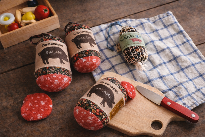 Handmade fabric salami toys with slices styled on a wooden table for pretend play