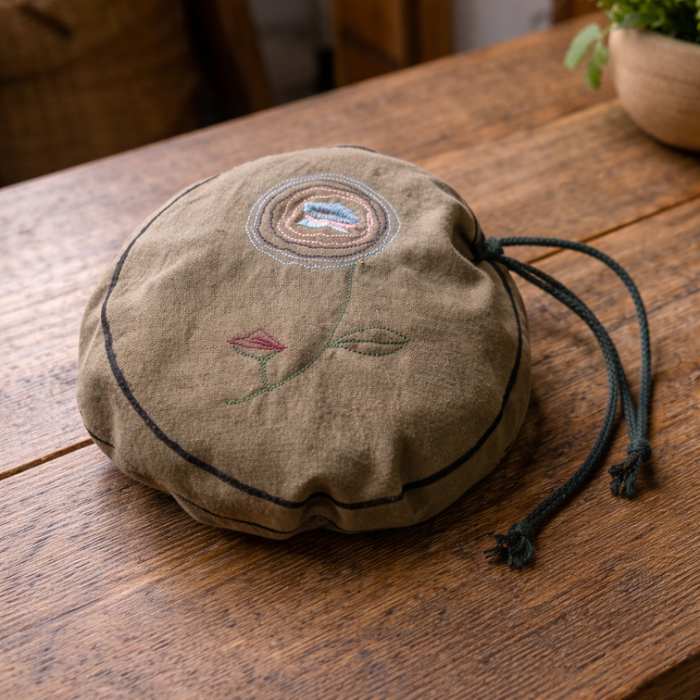 Embroidered fabric pouch with fabric waffle play set on a wooden surface